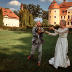 Braut und Bräutigam fangen einen Brautstrauß im Freien vor dem Schloss in Milkel. Foto: © Roman Koryzna, Schloss Milkel, 2023. Hochzeitsfotograf für Bautzen Dresden und die Lausitz.