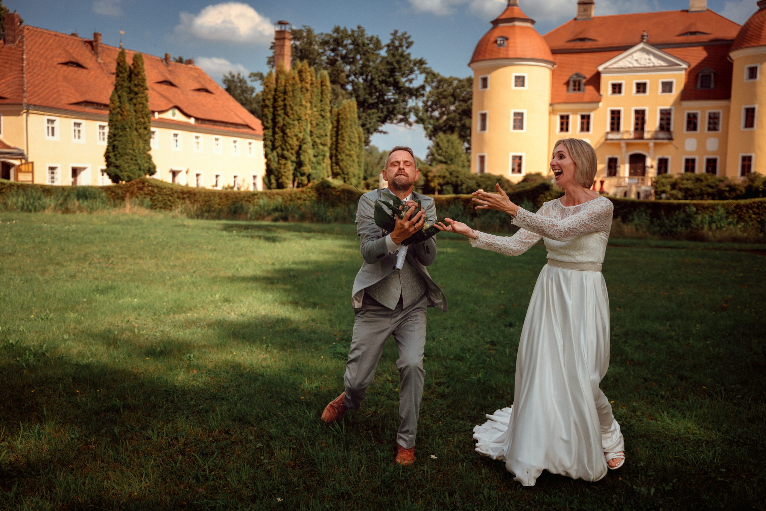 Hochzeitsfeier mit Braut und Bräutigam im Freien Braut und Bräutigam fangen einen Brautstrauß im Freien vor dem Schloss in Milkel. Foto: © Roman Koryzna, Schloss Milkel, 2023. Hochzeitsfotograf für Bautzen Dresden und die Lausitz.