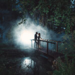 Paar steht auf einer Brücke in einem nebligen Wald mit Licht im Hintergrund. Foto: © Hochzeitsfotograf Roman Koryzna, August 2022. Hochzeitsfotograf für Bautzen und Dresden
