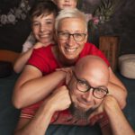 Familienporträt mit einer Frau, einem Mann und zwei Jungen, die lächeln und aufeinander liegen. Fotograf: © Roman Koryzna, Familienfoto, Studio Koryzna, Fotostudio, Radibor, Bautzen